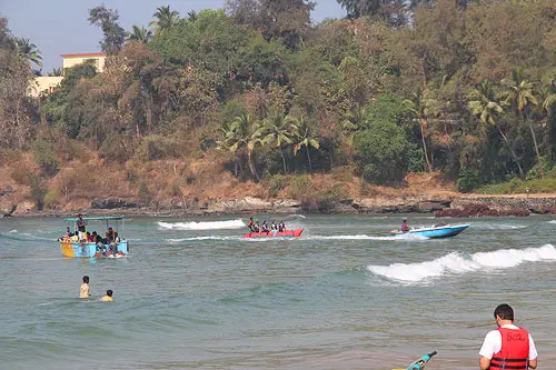 A speedboat pulls a red passenger raft boat. 